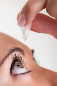 Woman dropping eye drops to treat dry eye